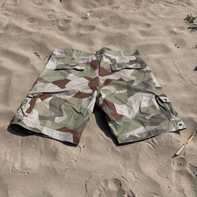 The back of a pair of Camp Shorts M90K Desert from TAC-UP GEAR  lying flat on the sand