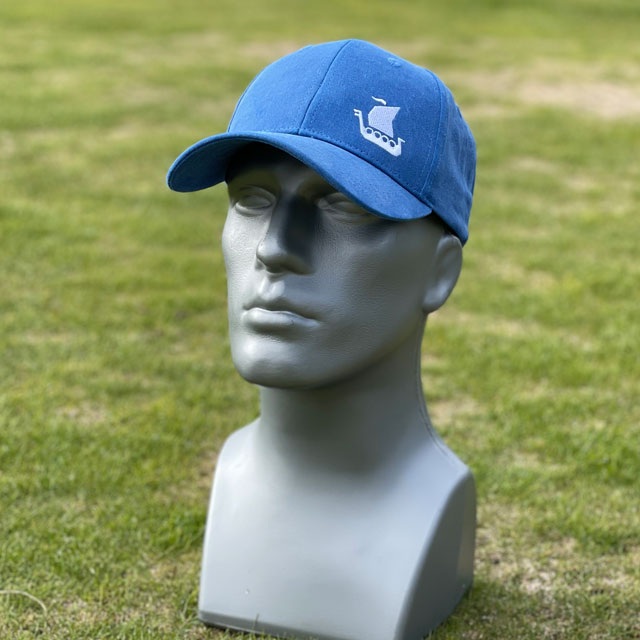 A Baseball Cap Blue from TAC-UP GEAR on a mannequin seen from an angle at the side showing the viking ship embroidery