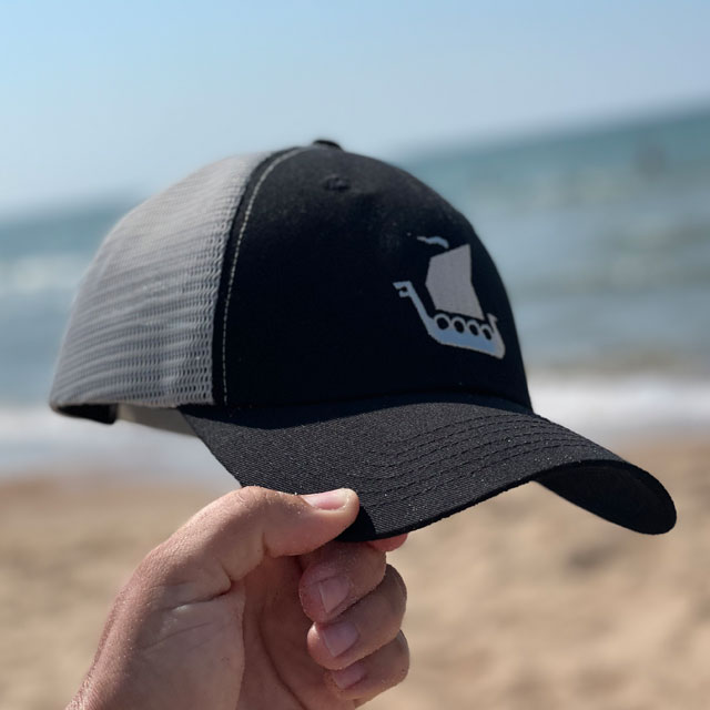A Mesh Cap Black and Grey on the beach with ocean background