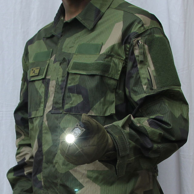 Slight sideview of a Field Shirt M90 and holding a sidewinder flashlight.