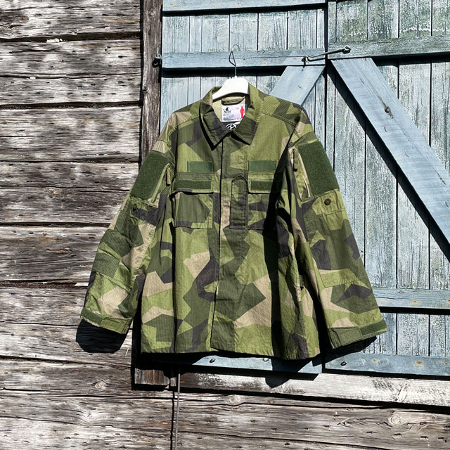 Our popular Field Shirt M90 hanging on a wooded buildning as background