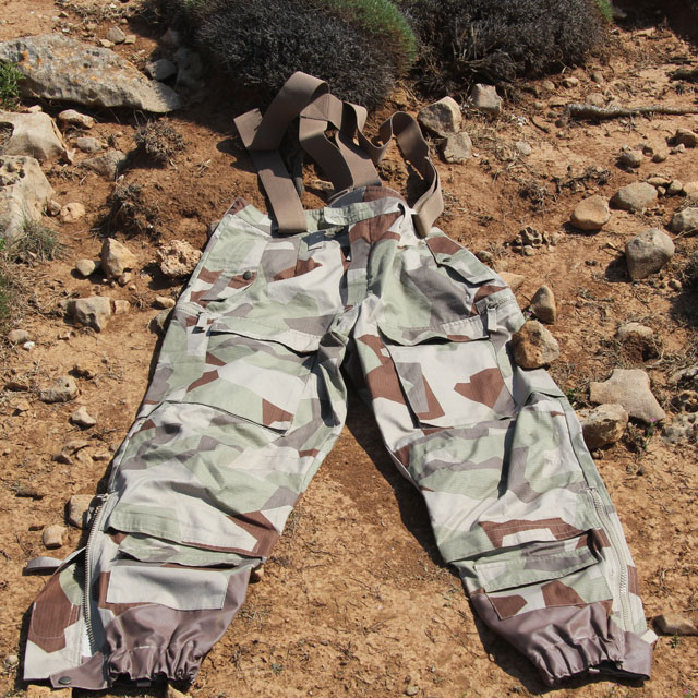 Lying flat on the coyote brown ground, a pair of Field Trousers M90K Desert.