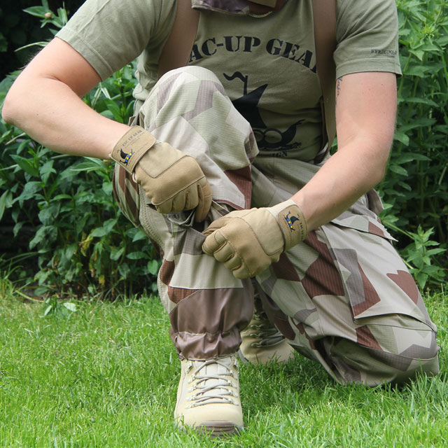 Kneeling wearing a pair of Field Trousers M90K Desert showing the pocket down by the boot.