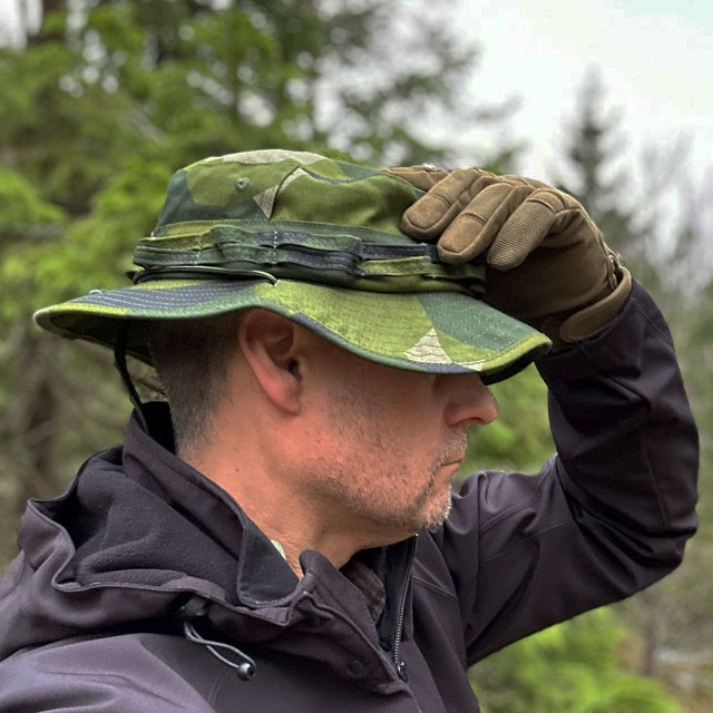 A Floppy Hat M90 NCWR from TAC-UP GEAR seen on model in the Swedish forest with a DropZone Gloved hand putting it on