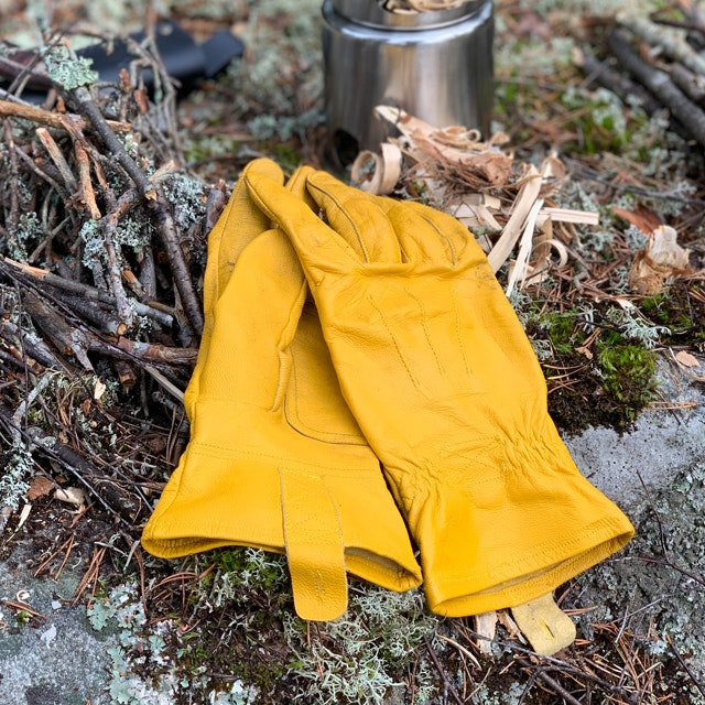 A pair of Bushcraft Leather Glove near a stove in the Swedish forest