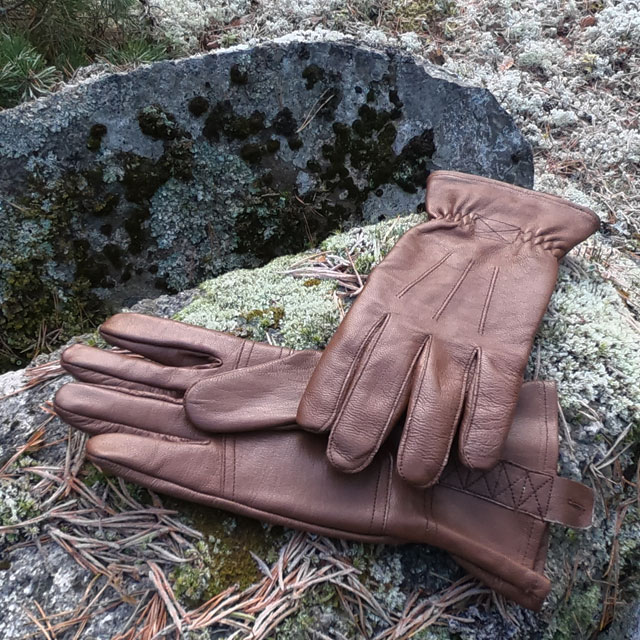 A pair of Bushcraft Leather Glove Brown from TAC-UP GEAR on a mossy and frozen stone