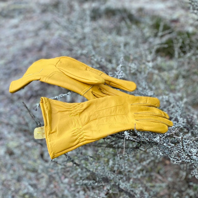 A pair of Bushcraft Leather Glove Cavalry from TAC-UP GEAR  on frozen forest floor