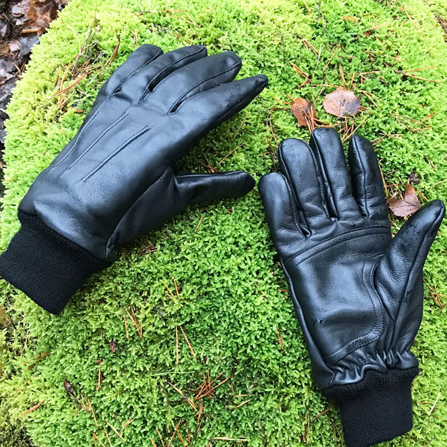 Autumn green mossy stone with a pair of Officer Black Leather Gloves on it.