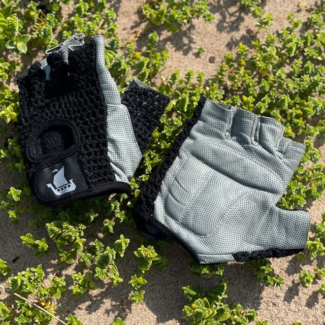 A pair of Training Glove Net Black lying flat on the sandy ground