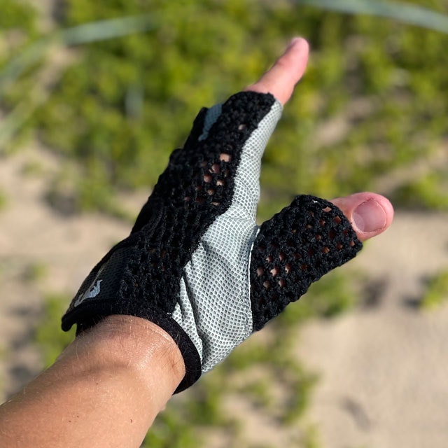 The side of a Training Glove Net Black with beach sand and green background