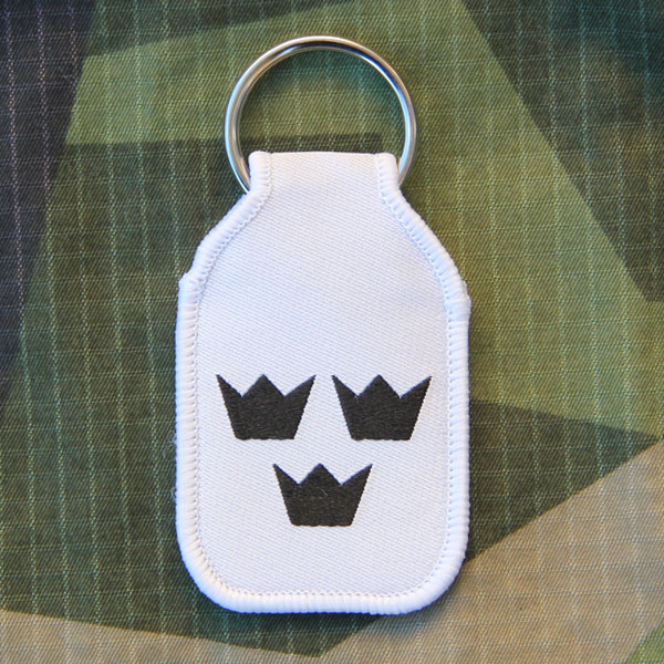 Keyring White With Crowns in a M90 camouflage background.