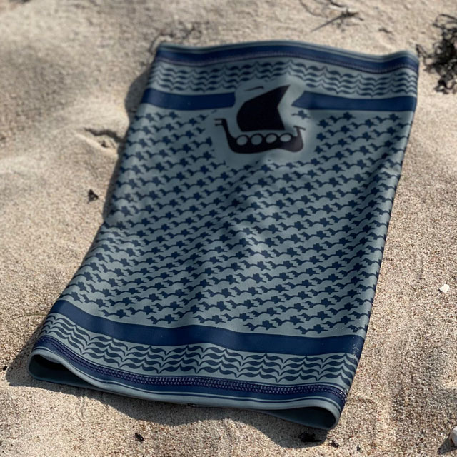 A Neck Tube Shemagh Navy Grey from TAC-UP GEAR lying flat on a sandy beach seen from above
