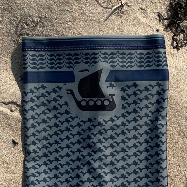A closeup of a Neck Tube Shemagh Navy Grey from TAC-UP GEAR lying flat on a sandy beach