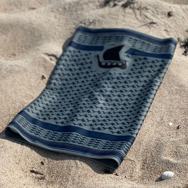 A Neck Tube Shemagh Navy Grey from TAC-UP GEAR lying flat on a sandy beach