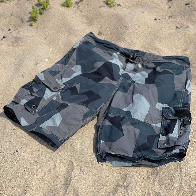Seen slightly from the side is a pair of NEPTUNE Shorts M90 Grey laying flat in the sun