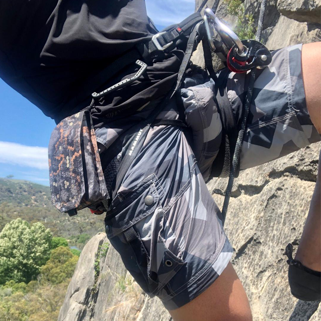 NEPTUNE Shorts M90 Grey on a climber with rock and sky background