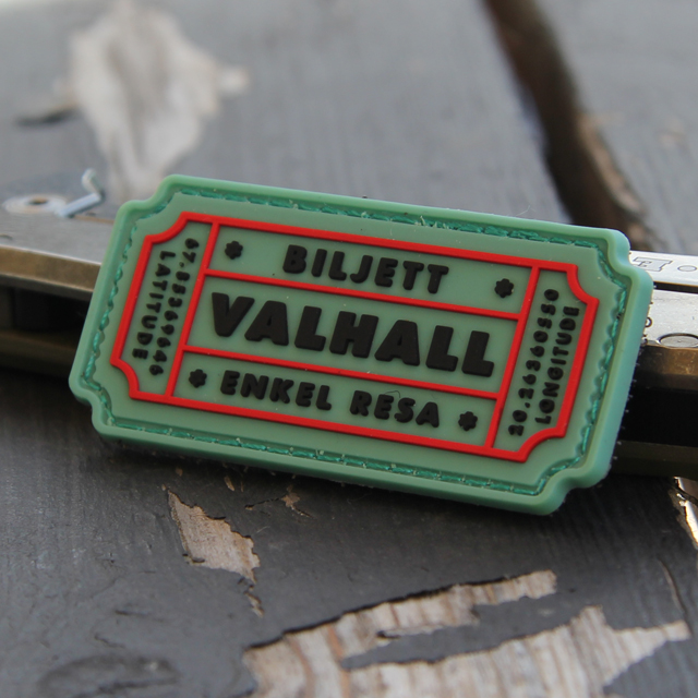 Ett Biljett Valhall PVC Ljusgrön märke mot en träbakgrund.