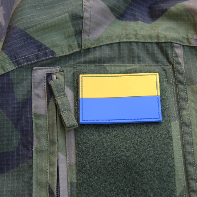 Blå-Gul Hook PVC Patch mounted on arm of a M90 camouflage jacket.