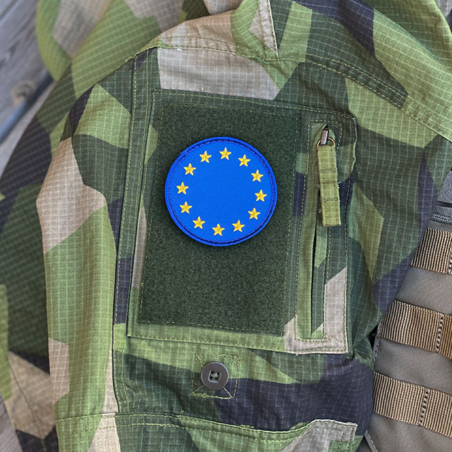 A EU Round Blue Hook Patch from TAC-UP GEAR mounted on a M90 Field shirt arm