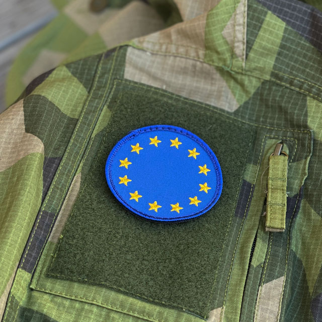 A EU Round Blue Hook Patch from TAC-UP GEAR mounted on a M90 Field shirt sleeve