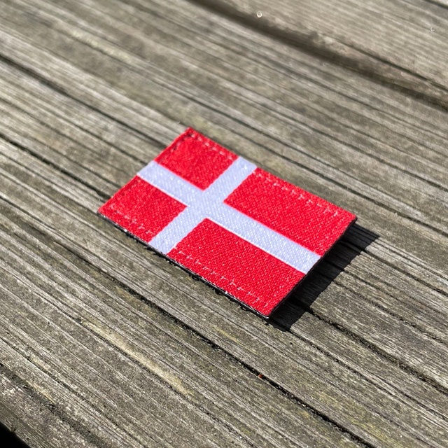 Denmark Flag Hook Patch Small from TAC-UP GEAR lying flat on wood seen from an angle