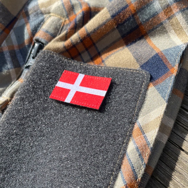 A Denmark Flag Hook Patch Small from TAC-UP GEAR mounted on loop fabric on a shirt