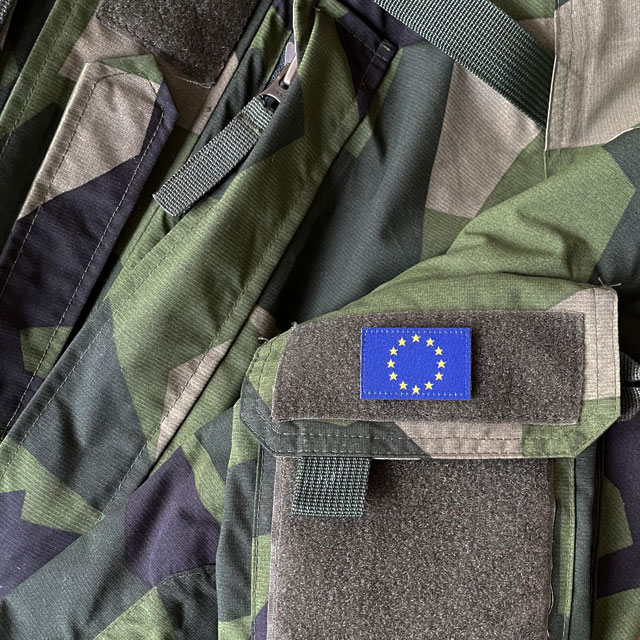 A Blue and yellow EU Flag Hook Patch Small from TAC-UP GEAR on a M90 NCWR Jacket arm pocket seen full front