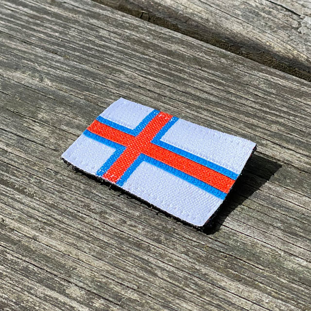 Faroese Flag Hook Patch Small seen from an angle lying on wooded floor