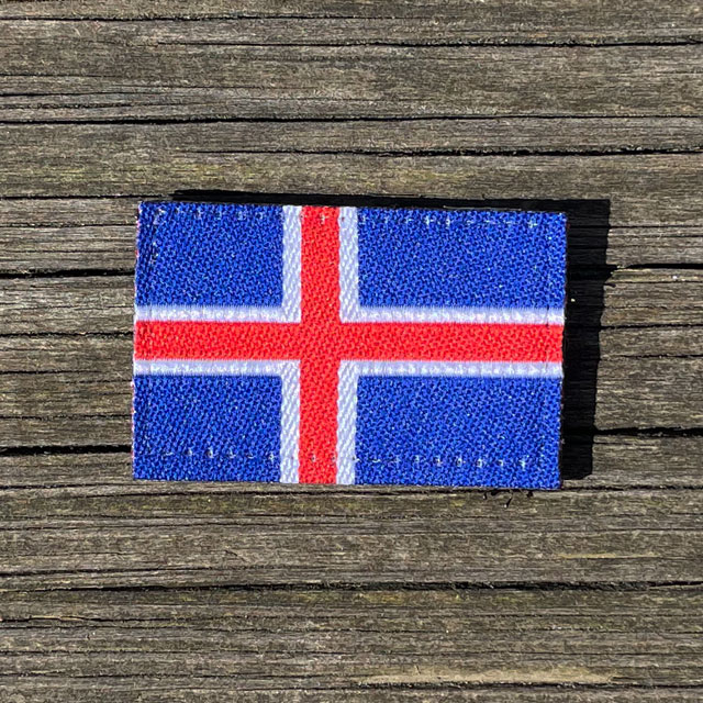 A Iceland Flag Hook Patch Small from TAC-UP GEAR laying on wooded a plank