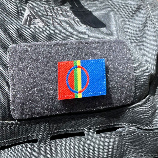 A Sámi Flag Hook Patch Small from TAC-UP GEAR mounted with hook and loop on a grey rucksack seen from an angle