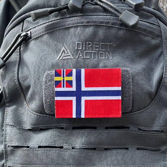 Norges handelsflagga 1844–1898/99 som ett tygmärke med kardborre på baksidan färst på en grå ryggsäck sedd framifrån