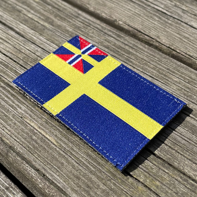 Sveriges handelsflagga 1844–1905 från TAC-UP GEAR sett från sidan liggandes på brädor