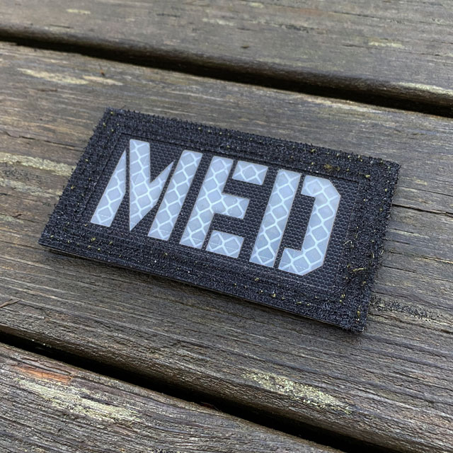 White text on a IR - MED Black-Green Reversible Glow Hook Patch
