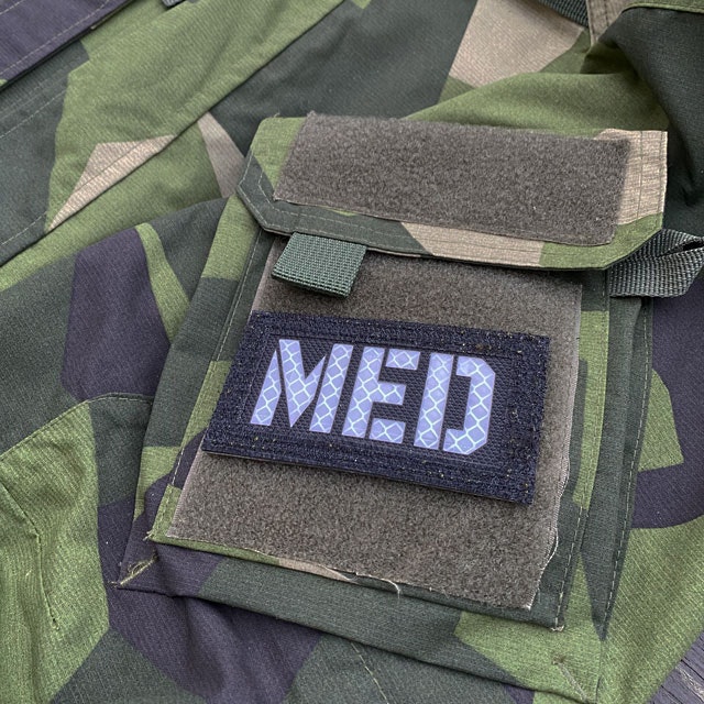 A IR - MED Black-Green Reversible Glow Hook Patch mounted on a M90 sleeve black side out seen from the side