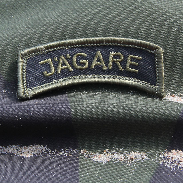 M90 camouflage background and a JÄGARE Patch Green/Black/Green M14.