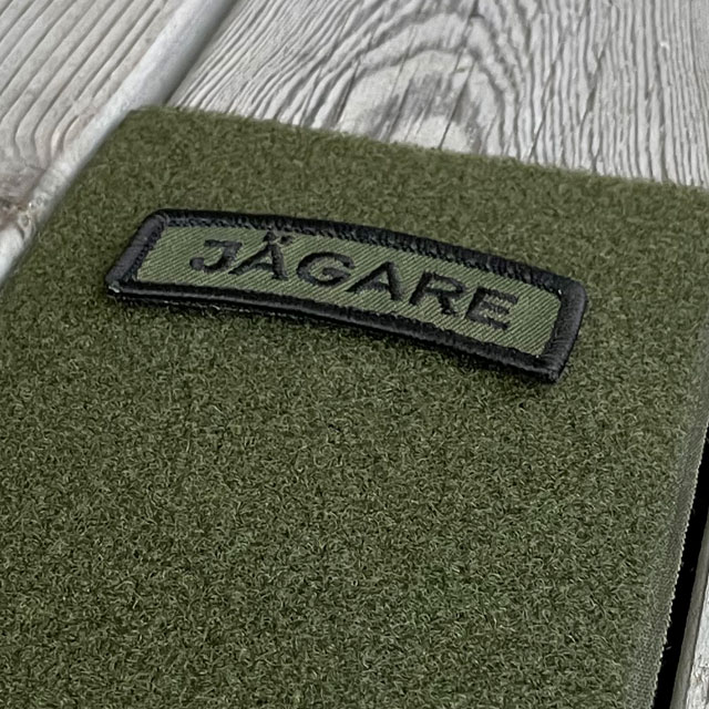 A JÄGARE Hook Patch Black/Green from TAC-UP GEAR on green loop fabric seen from an angle