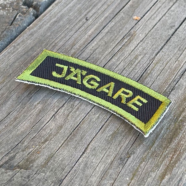 A JÄGARE Patch Jungle Green on a wooded background seen from an angle