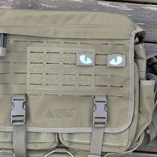 A pair of Lynx Glow Eyes Green Hook Tube mounted on a green messenger bag from Direct Action