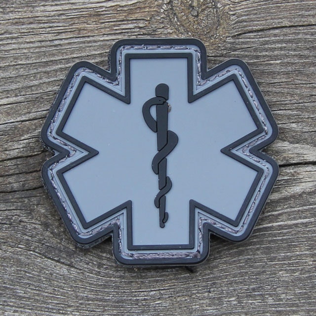 Wood background and a MEDIC PVC Star Black Grey Hook Patch.