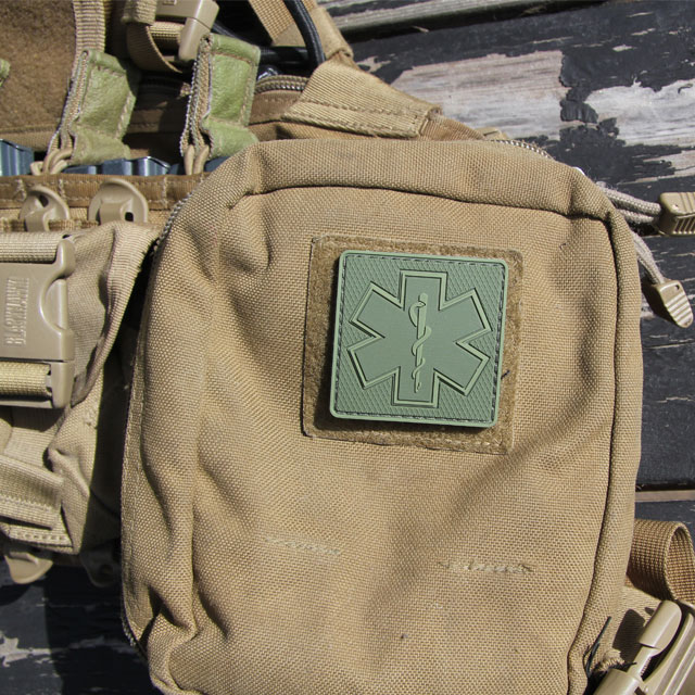 A MEDIC Subdued Green Star Hook PVC Patch mounted on a desert colored pouch.