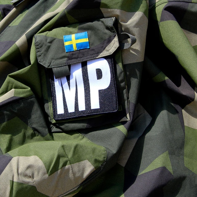 En Militärpolis Large Patch monterad på en M90 kamouflage jacka.