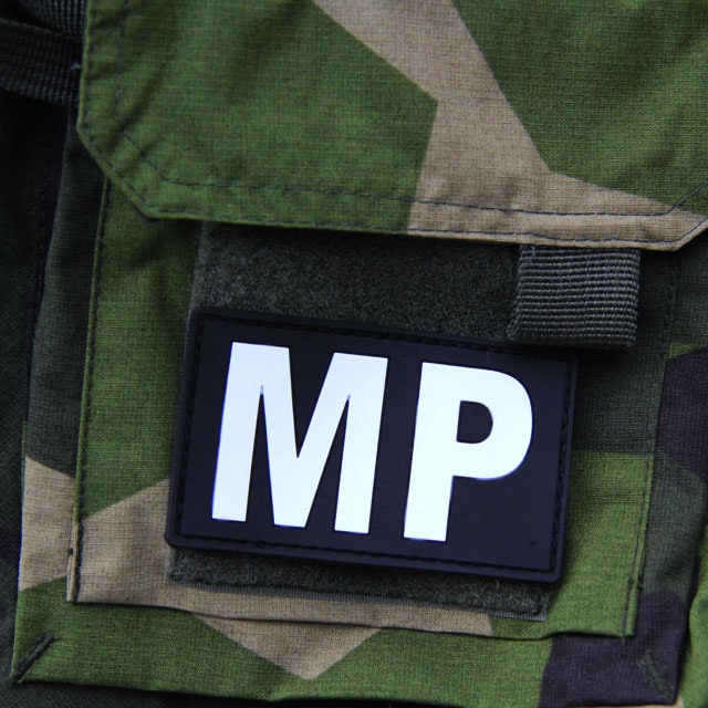 En Militärpolis PVC Patch monterad på ärmen på en M90 kamouflage jacka.