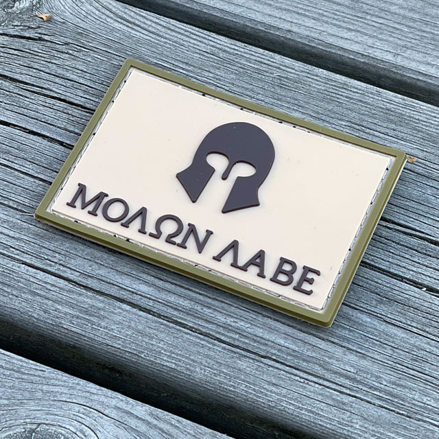 Molon Labe Multi Tan PVC Patch from TAC-UP GEAR with a wooded floor background