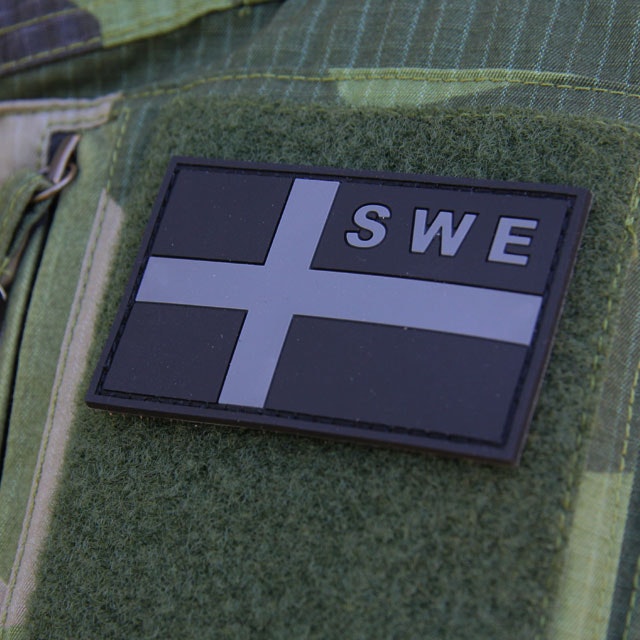 A mounted Sweden Flag OPS PVC Black/Grey Patch on the arm of a Field Shirt M90.