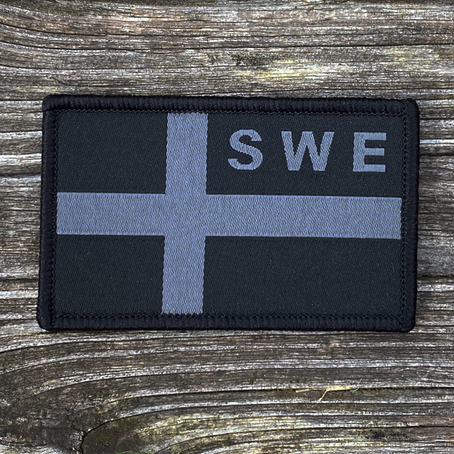 A Sweden Flag OPS Nylon Black/Grey Patch on wooded floor