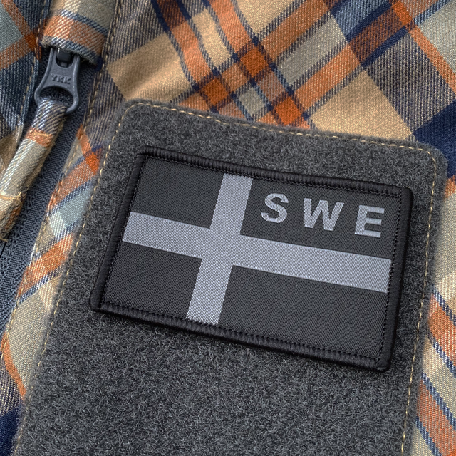 A Sweden Flag OPS Nylon Black/Grey Patch seen slightly from the side mounted with velcro on a shirt