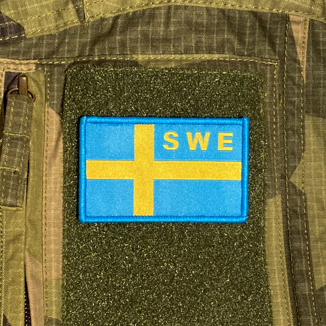 Sweden Flag OPS Blue Yellow Patch mounted on a M90 camouflage shirt sleeve