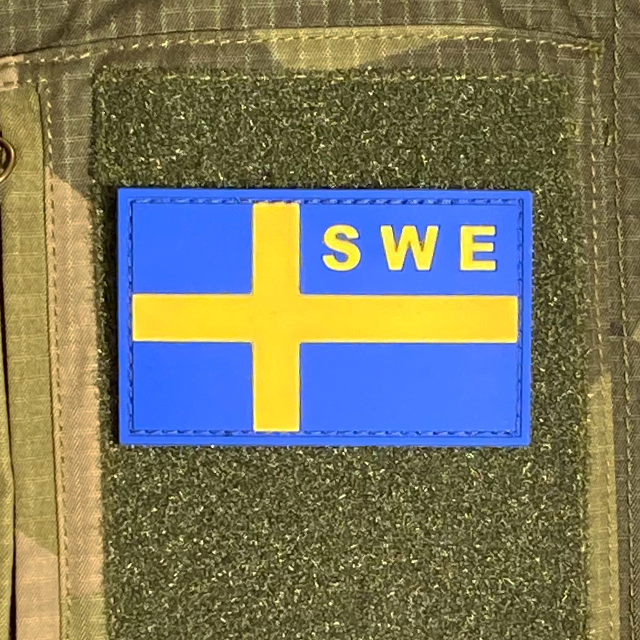 Sweden Flag OPS PVC Blue Yellow Patch mounted on a M90 camouflage shirt sleeve