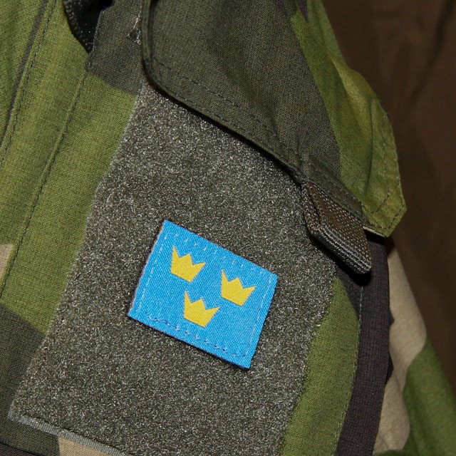 A Three Crowns Morale Patch is mounted on a NCWR M90 Camouflage jacket.