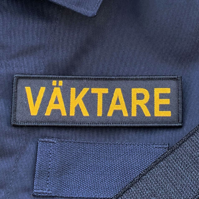 VÄKTARE Avlång Kardborremärke på en blå uniform